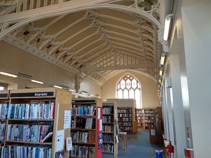 image of Shrewsbury Public Library, Shropshire, U.K.. This is a smaller room, two story room with a cream colored barrel vault ceiling. The shelves with modern books.