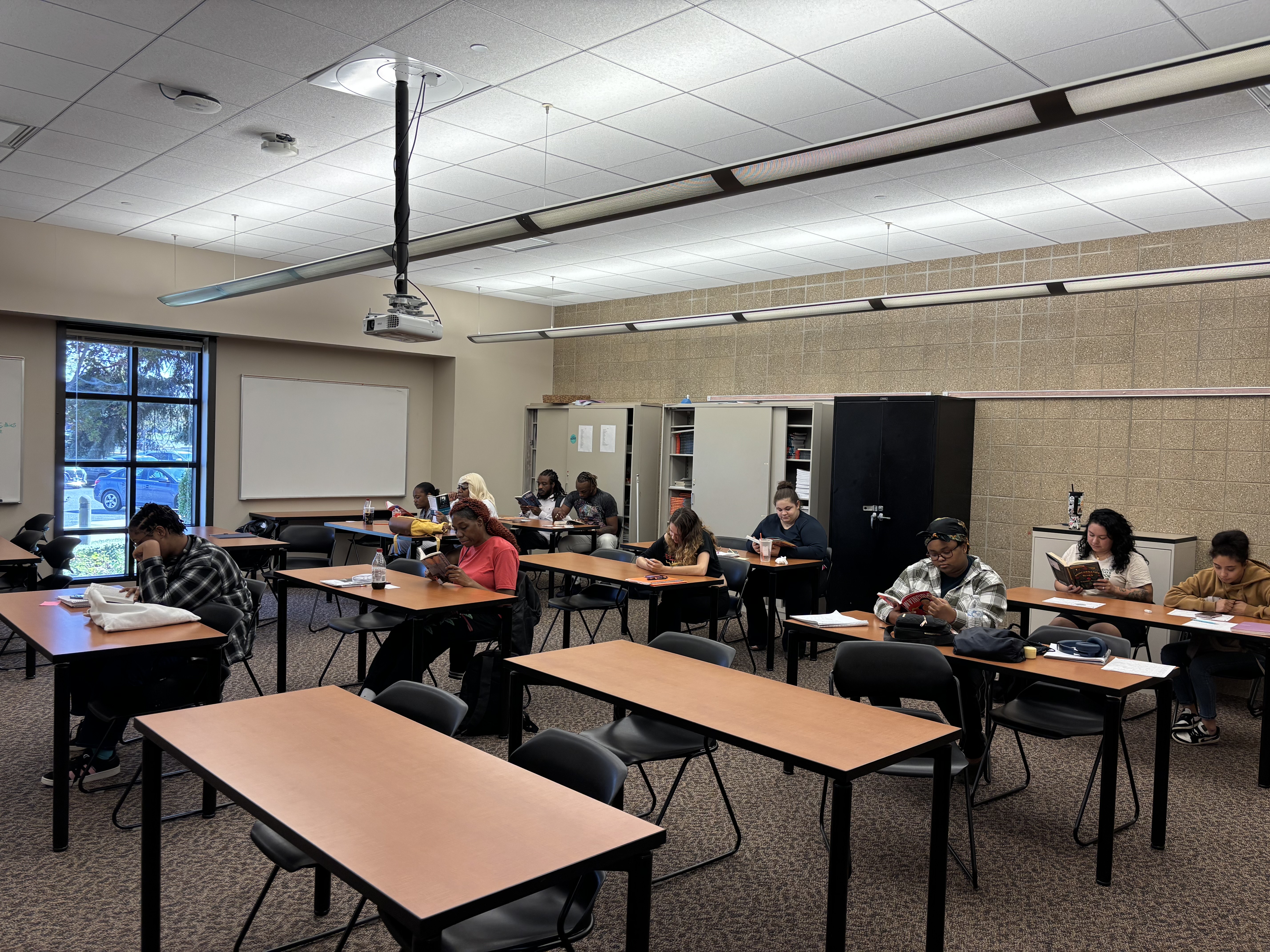 This is an image of 11 adult education students reading in a classroom.